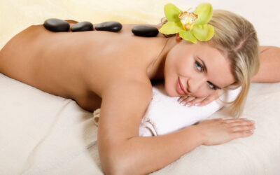 Young woman relaxing on the bed with flower and hot stones